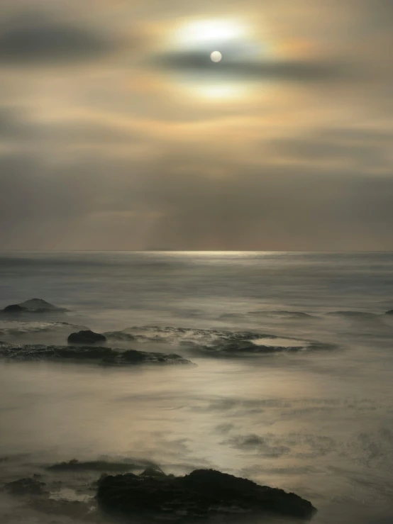 light shining over the ocean with dark clouds