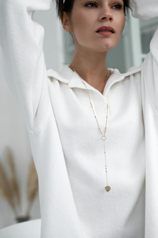 a woman in a white sweater holds her hand up with a hand