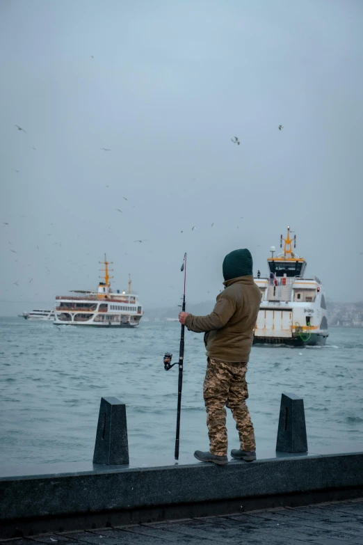 a person standing on the dock holding onto a fish pole