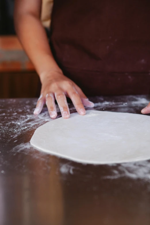 a person that is kneading dough on a table