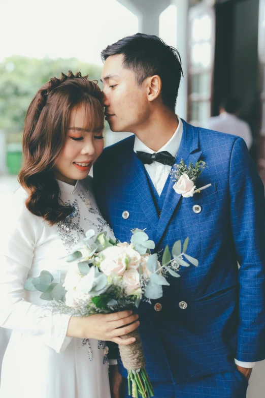 a couple is kissing while holding bouquets