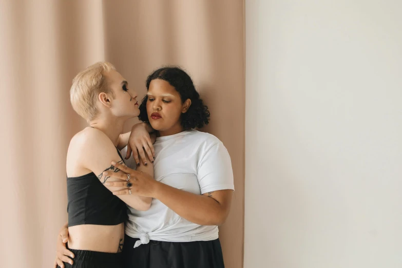 two women in black and white clothing are kissing one another