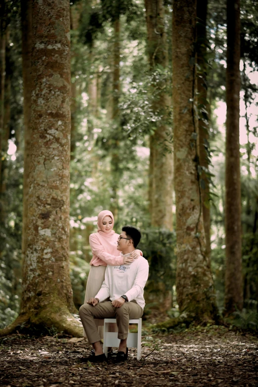 a couple sit on a bench in the middle of some trees