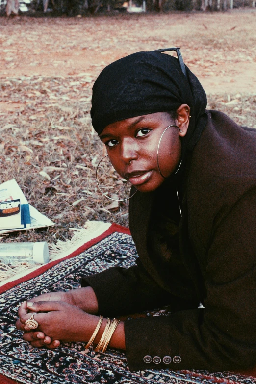 an african american woman sits on a red rug while looking to her left