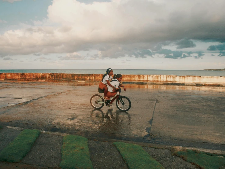 two people riding a bike near a beach