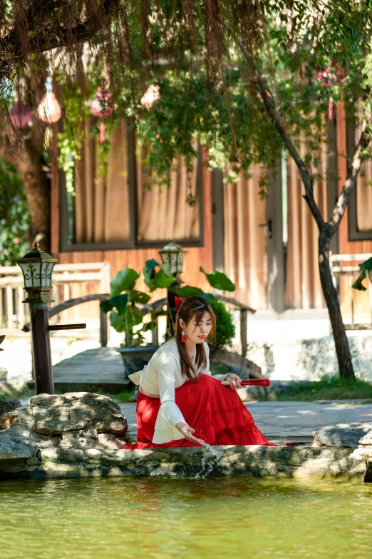 a woman in traditional garb sitting on a ledge above water