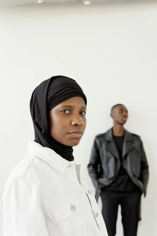 two people, each wearing a turban, are standing in front of a white wall