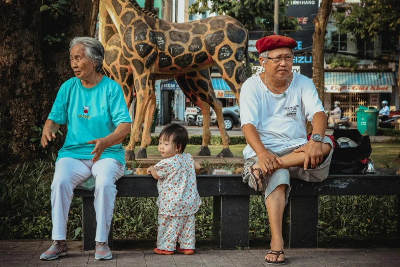 a little boy and a man sitting on a bench in front of a statue