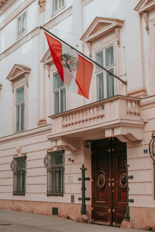 a tall building with a pair of doors and two red and white flags