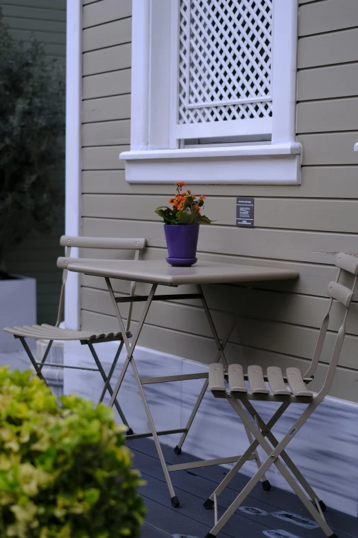 a couple of chairs and table sitting next to a house