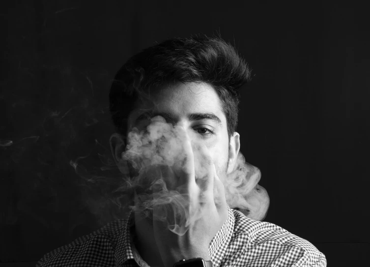 man looking at camera with his face obscured by smoke