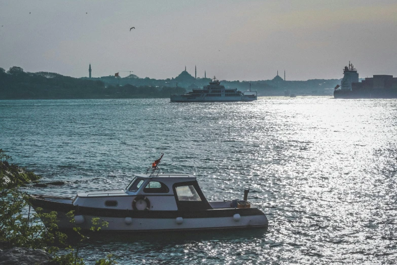 a small tug boat with two smaller boats in the background