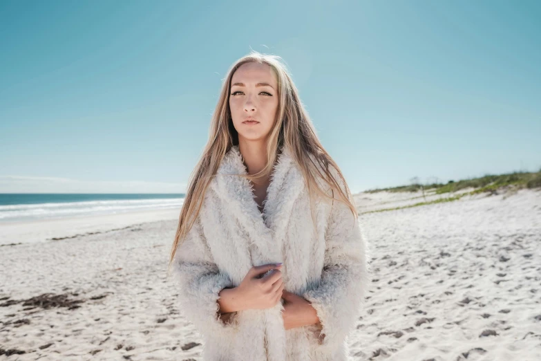 a girl with long blonde hair standing on a beach