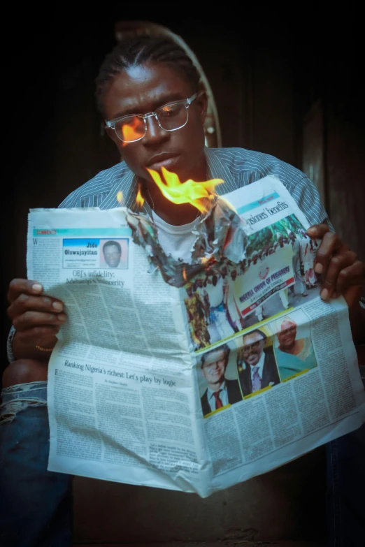 a man wearing glasses holding a bunch of papers with flame inside