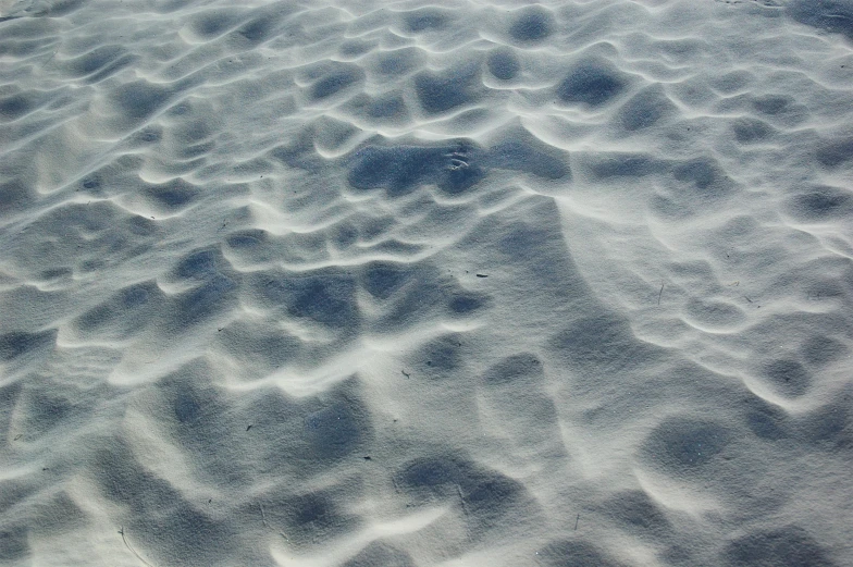 close up image of white sand and tracks on beach