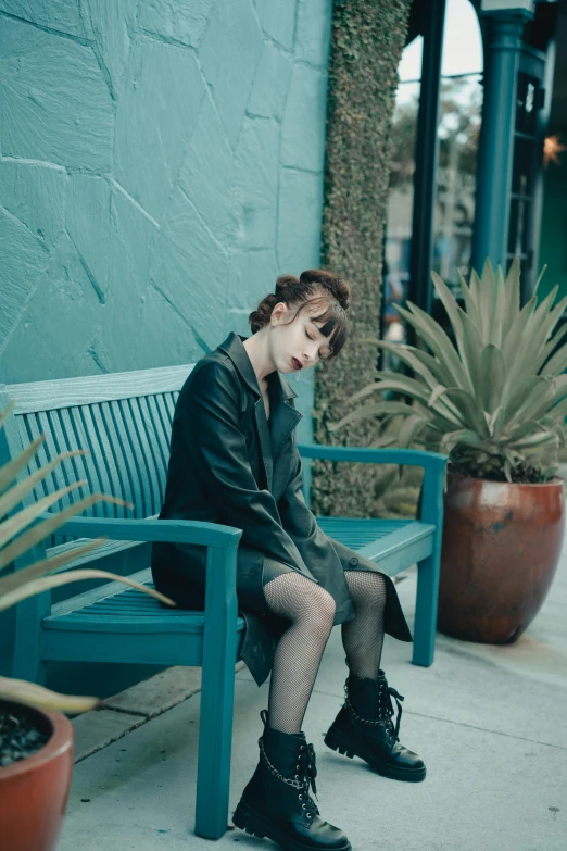 a young woman is sitting on a blue bench