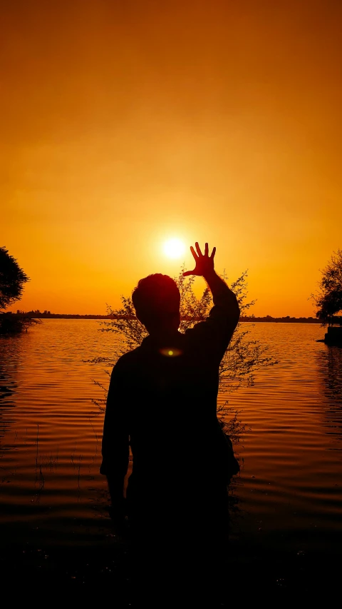 a person in the water, reaching into the sky to catch the sun