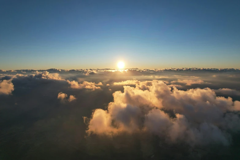 the sun rises over clouds at an angle