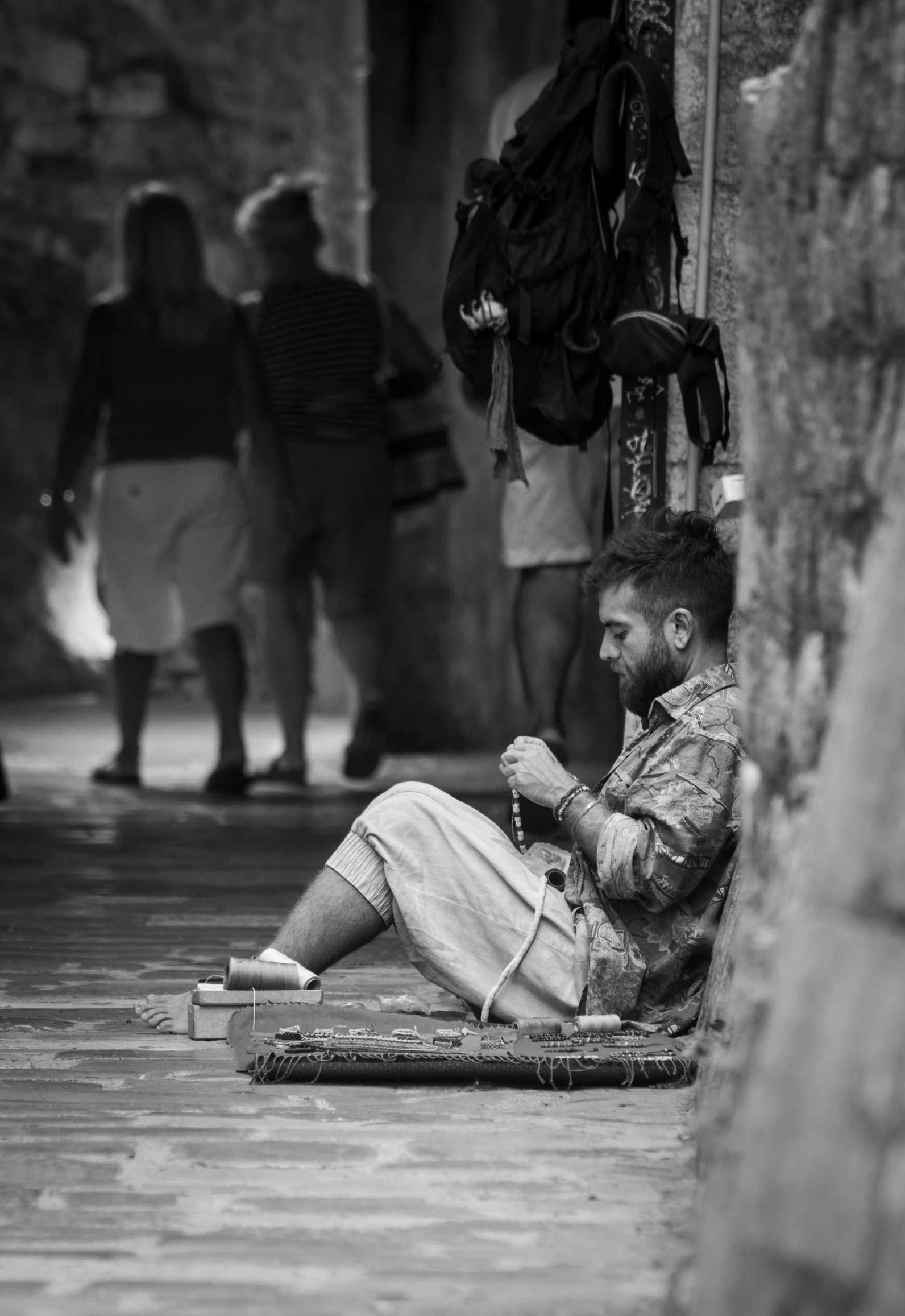 black and white image of man sitting outside on a street