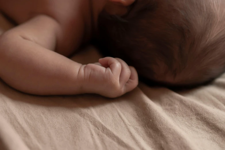 a baby wrapped up sleeping on top of a blanket