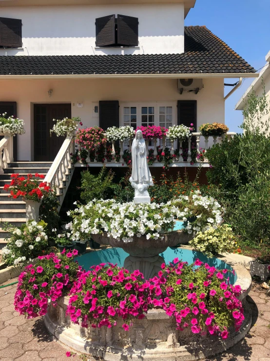 a building with a front porch, stairs, flowers and a statue