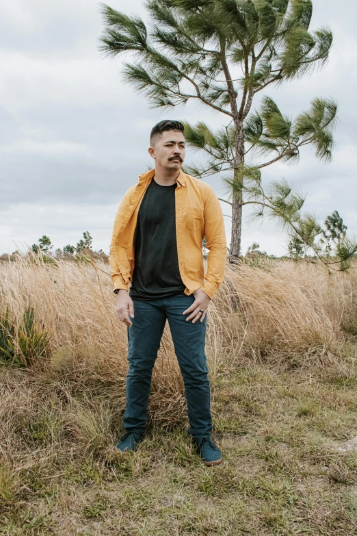 a man standing in a field wearing a orange jacket