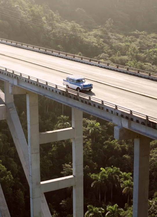 a blue bus on a highway next to an overpass