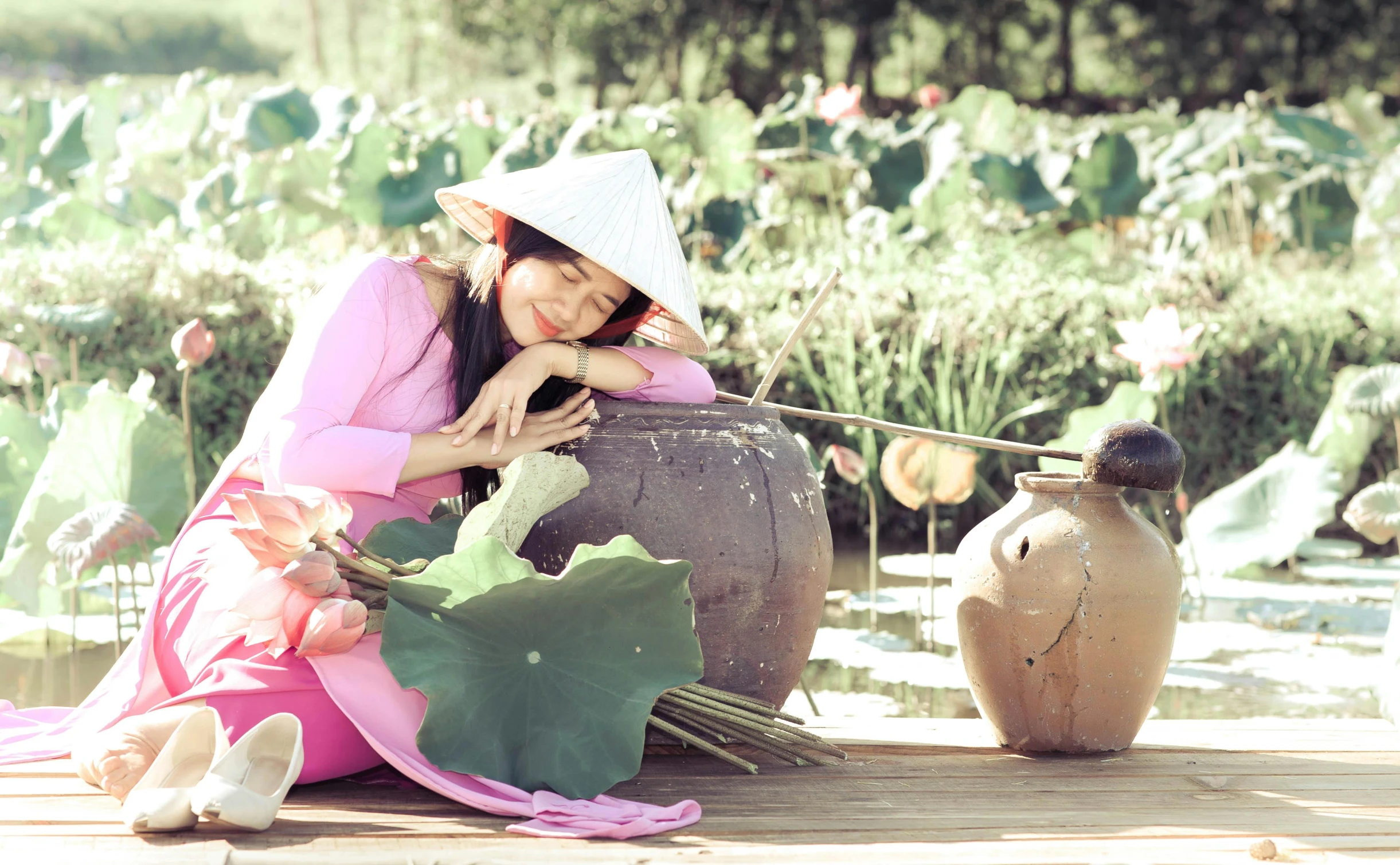 a woman in a pink dress sitting down on a bench near flowers