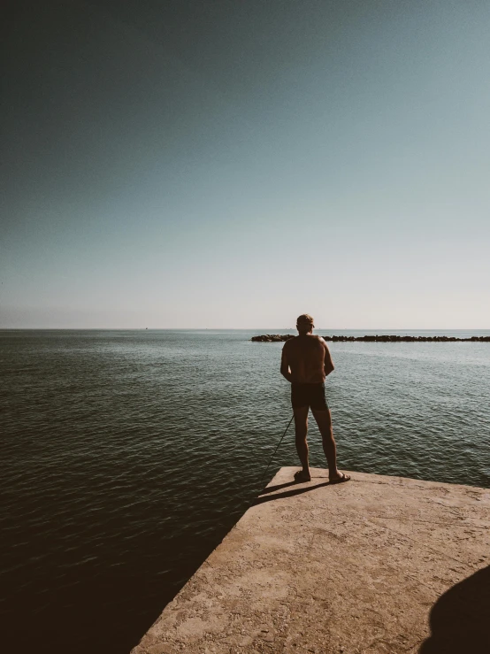 a man is standing on a pier looking out at the water