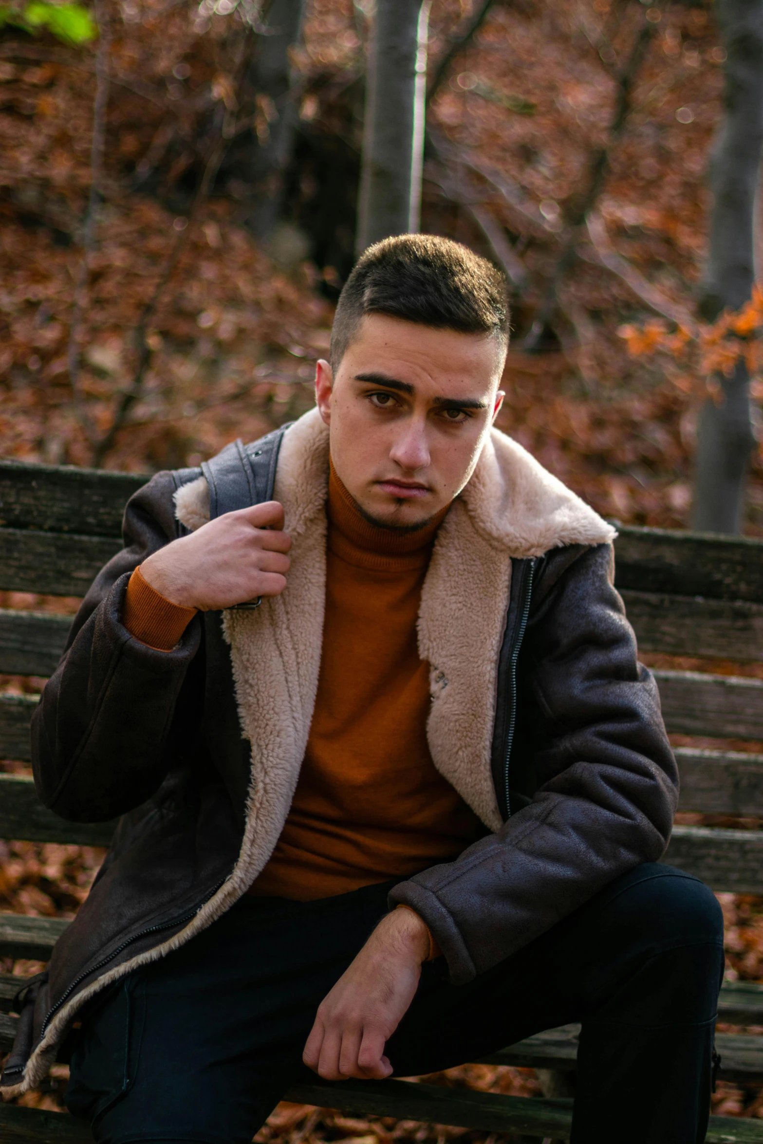 young man sitting on park bench posing for the camera