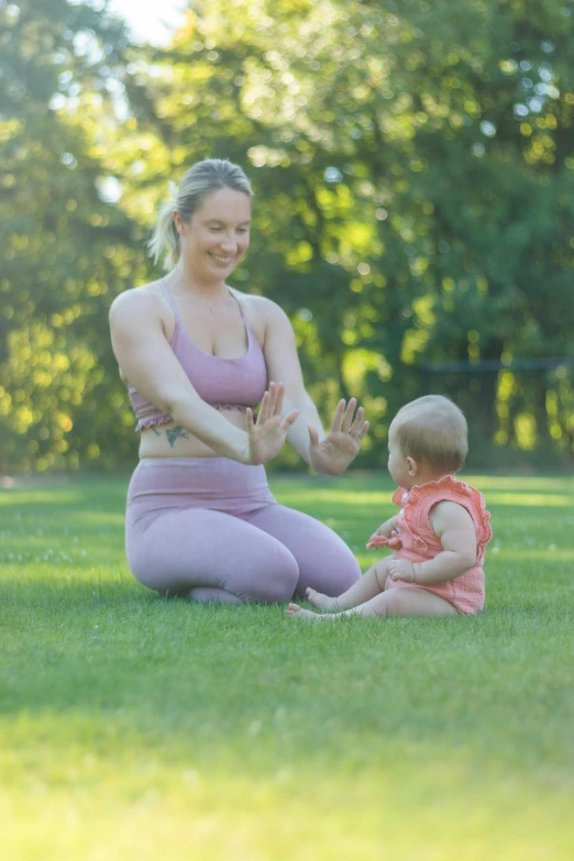 a woman kneeling down while holding a baby's hand