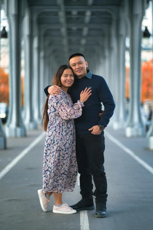 a couple hugging while standing next to each other on an overpass