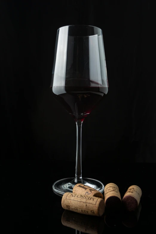 a wine glass with two corks sitting next to it