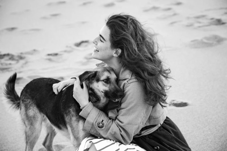 the woman is hugging her dog on the beach