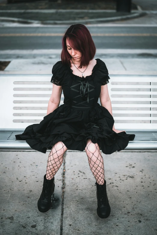 a woman in a gothic dress is sitting on a bench