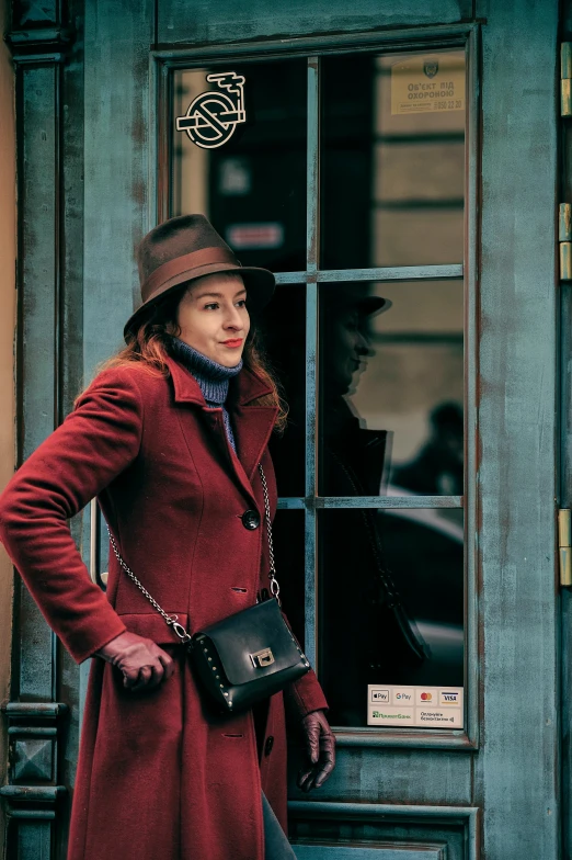 a woman in a long coat with a hat and purse