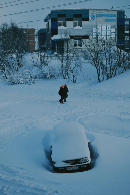 person walking on snow covered driveway near parked car