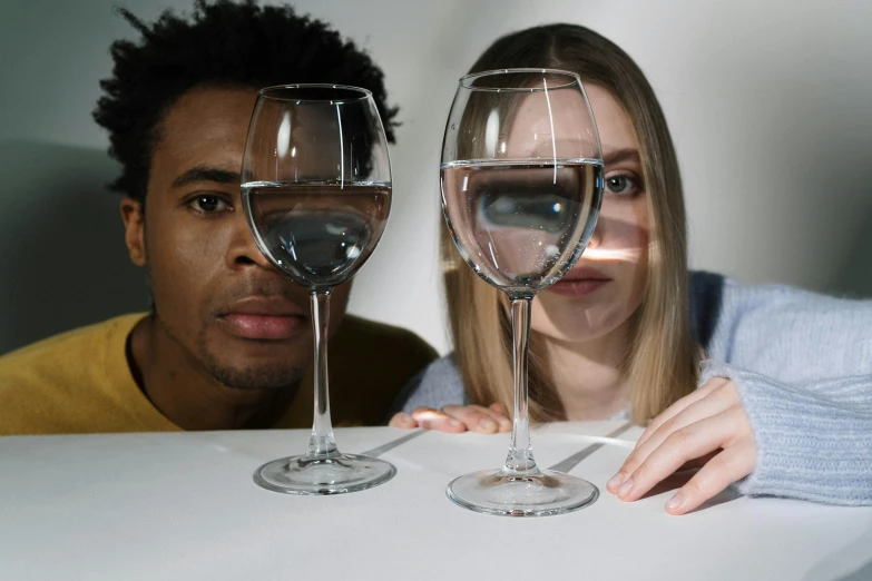 two people are sitting at the table with glasses