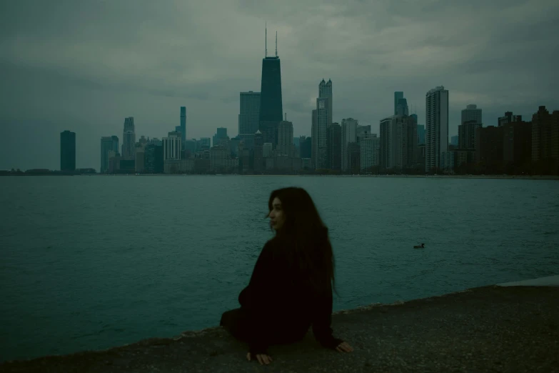 a woman is sitting by a body of water