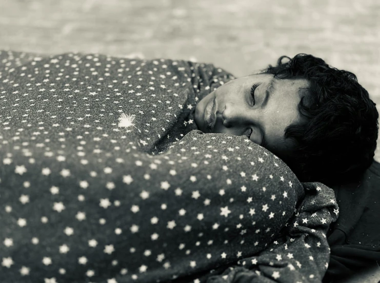 a young man laying down on top of a bed under covers