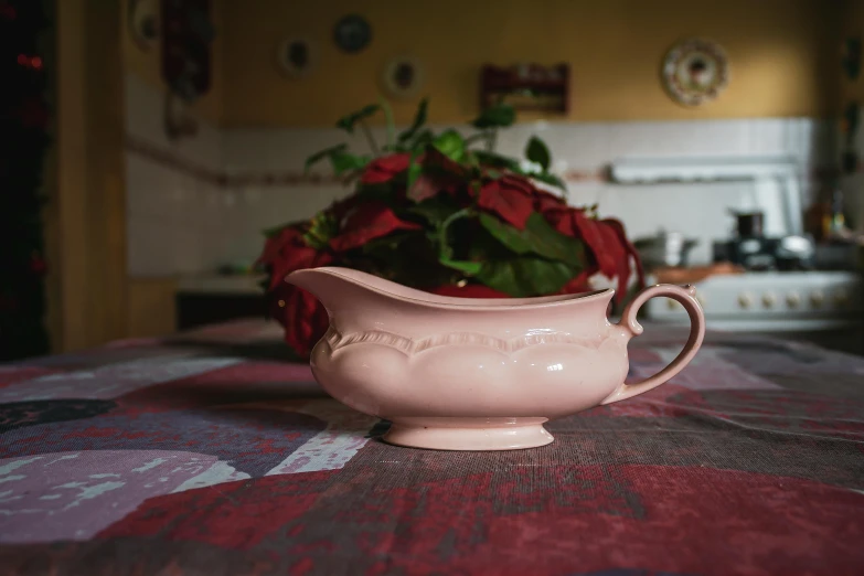 a creamer and red flowers on a table