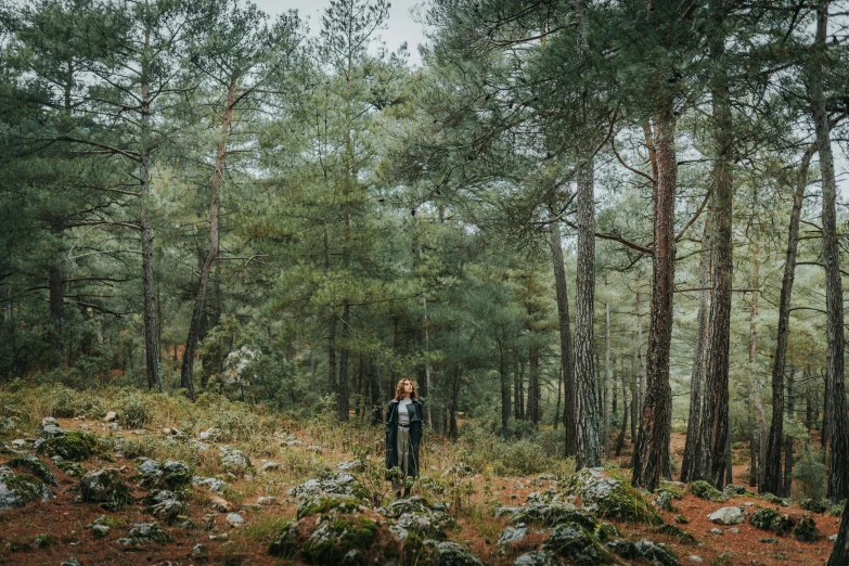 there is a woman standing alone in the woods