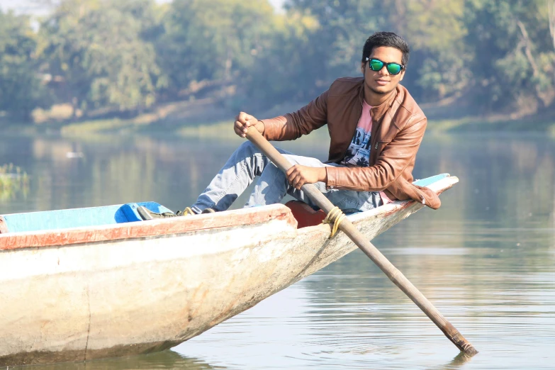 a man sitting on top of a boat with a pole in his hand