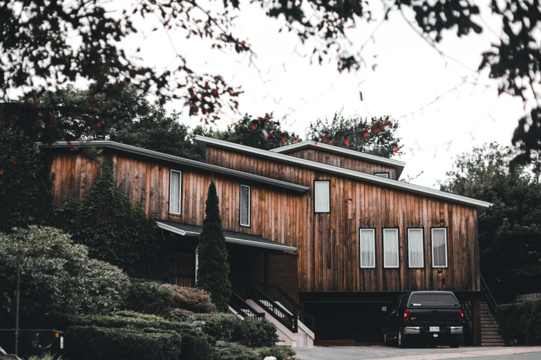 the back side of a wood home with a black car in front