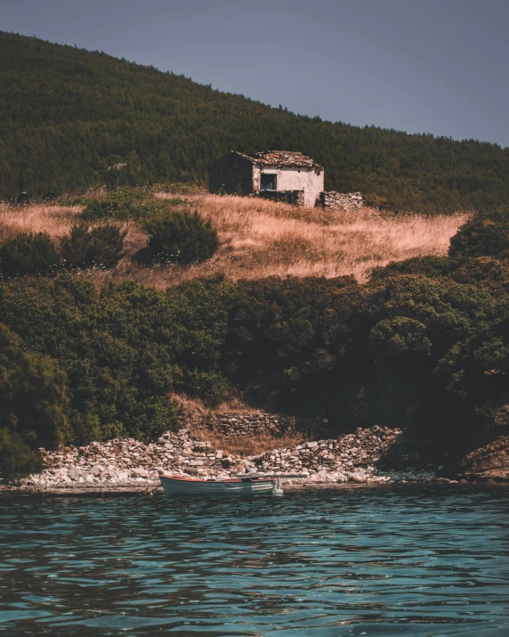 an old run down building on the side of a hill next to the ocean