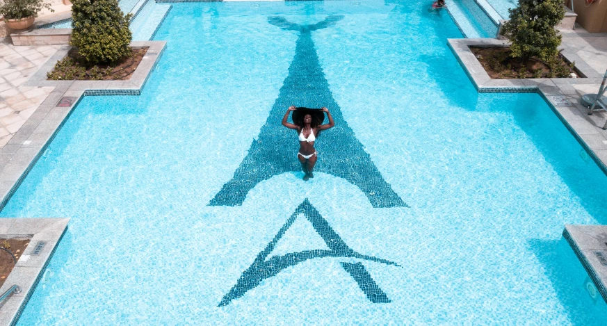 a woman walking through a pool with a man in the water