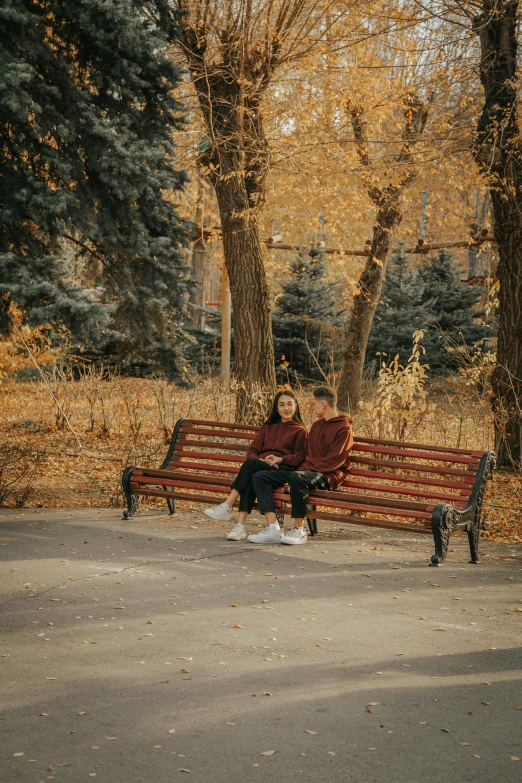 a woman is sitting on a bench in the park