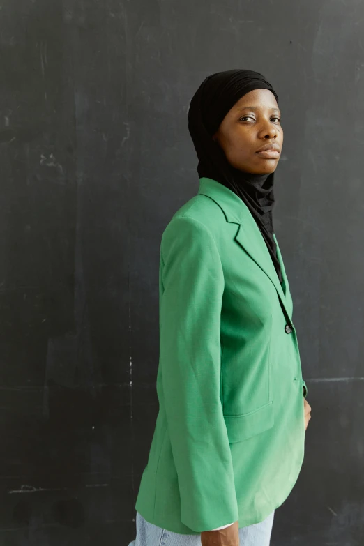 a woman is dressed in green and wearing pants and a scarf