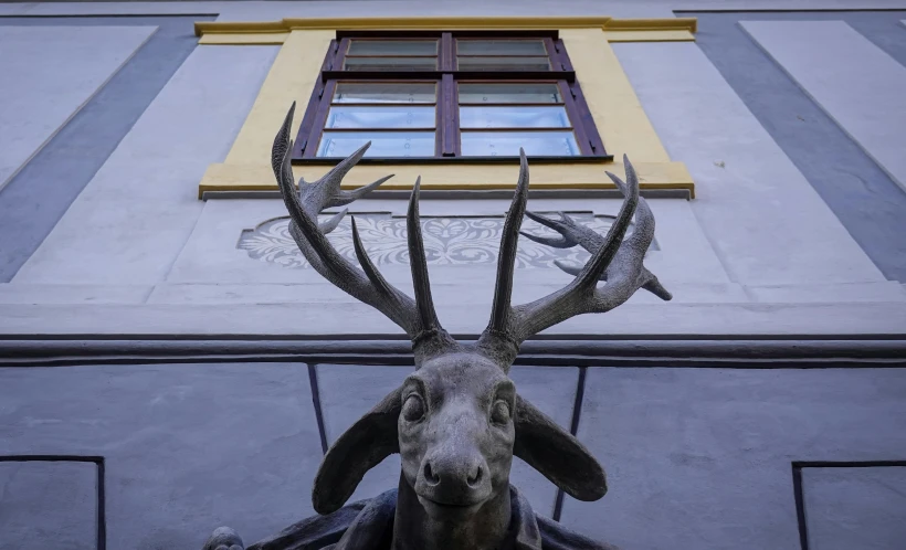 the statue of a deer head with horns in front of an art deco building