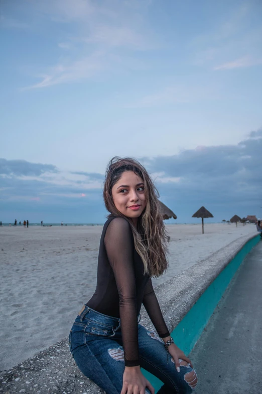 the girl poses near the beach in her black shirt and jeans